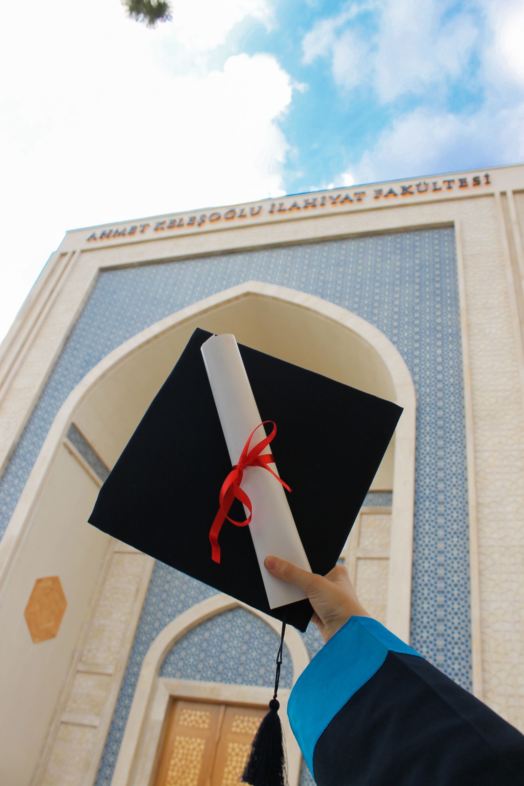 Celebrating graduation with a diploma and cap in front of a university.