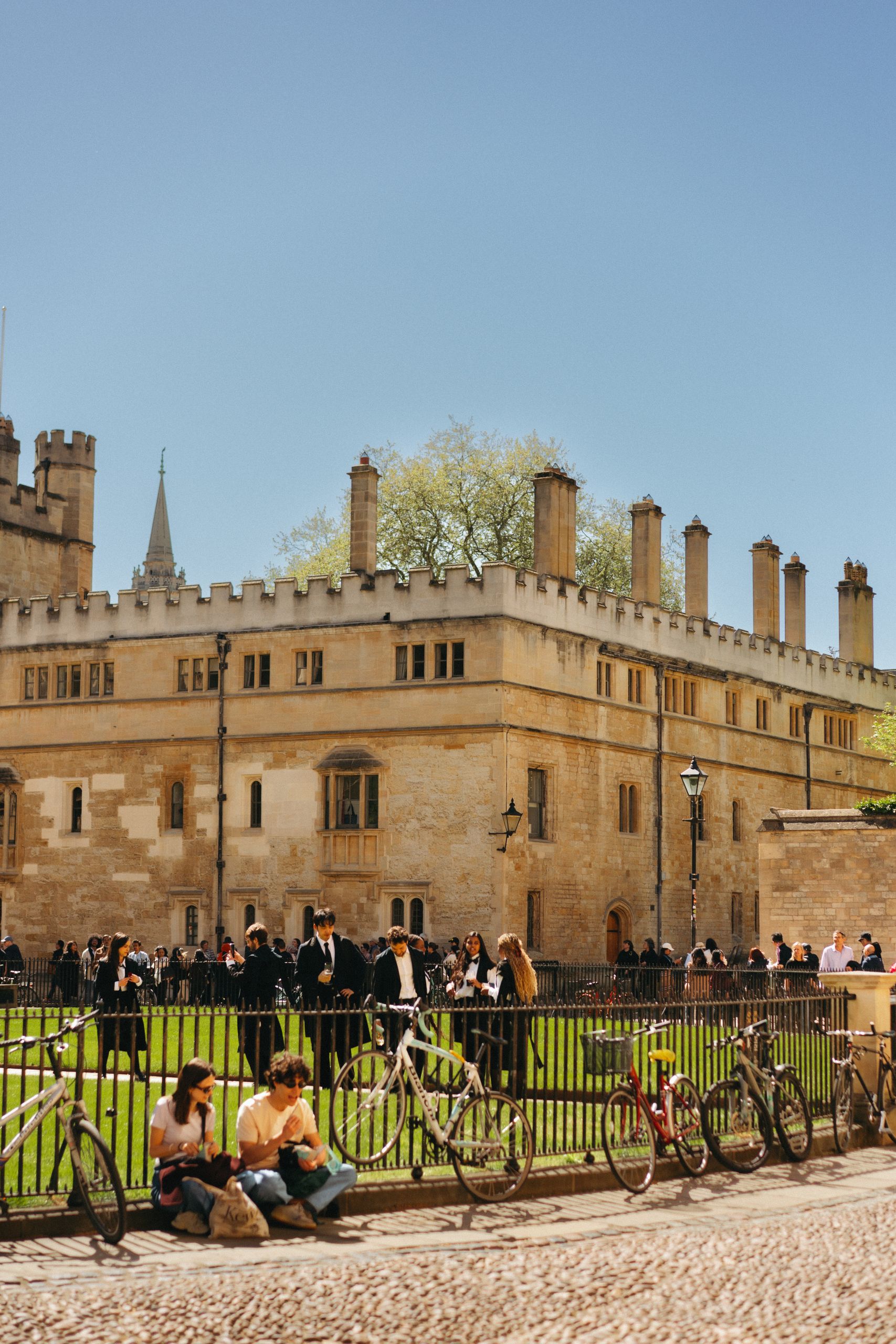 View of a historic Oxford university building with people and bicycles, symbolizing academic life.
